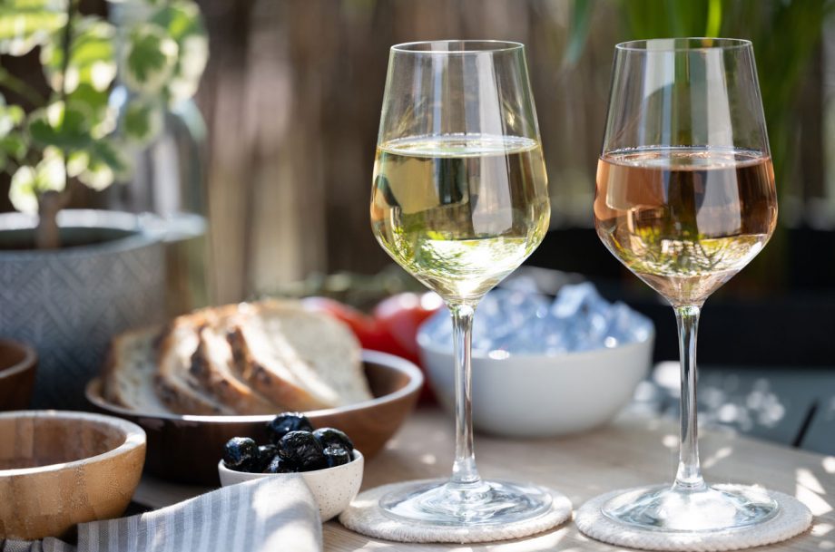 A glass of white wine and glass of rosé with food in outdoor setting